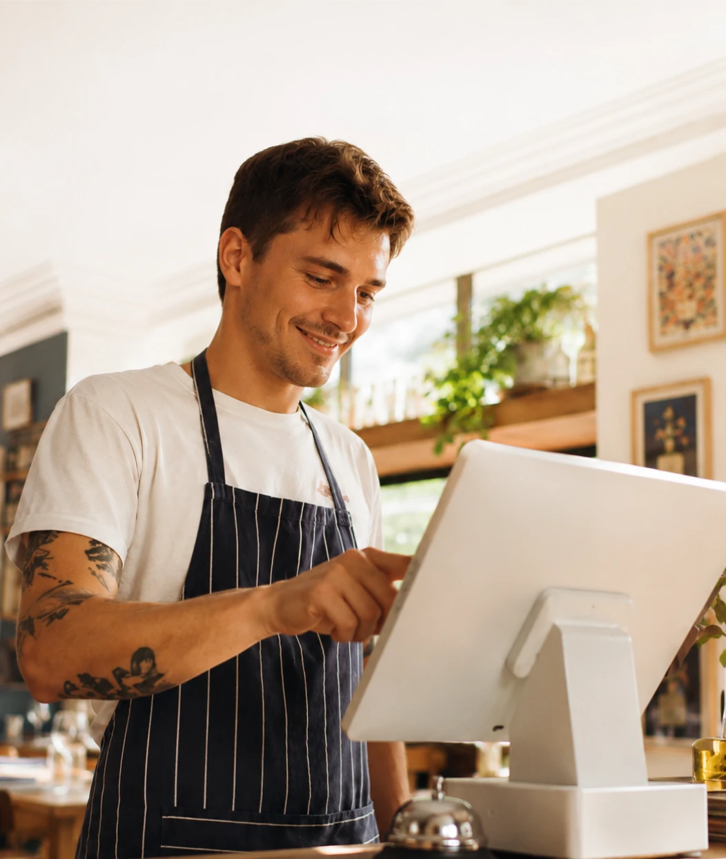 Camarero de un restaurante gestionando un pedido en la pantalla táctil del TPV
