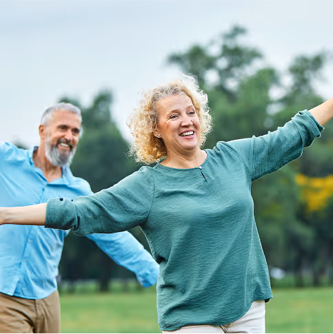 An older couple stretching together outdoors.