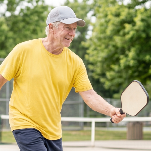 An older man enjoying a game of pickleball outdoors.