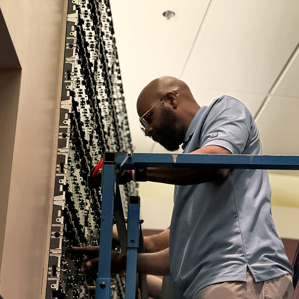 Technician wiring the back of an LED wall