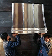 Dos operarios instalando una campana extractora de cobre — Amoretti Brothers