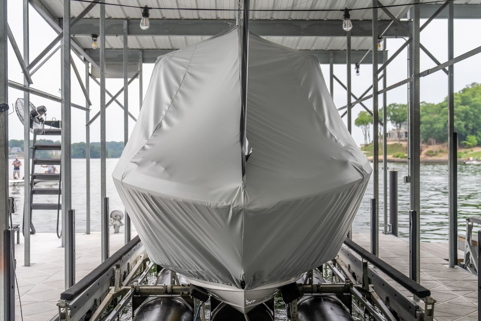 Boat fully wrapped in a gray custom cover on its lift