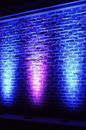 Bakstenen muur in blauw en paars licht van uplights
