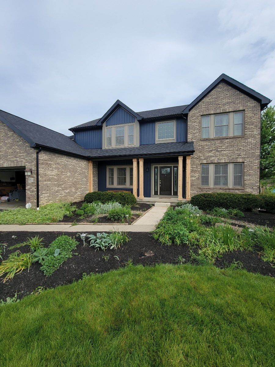 Front of the same home after exterior renovation by 614 Exteriors, with dark roof, dark siding and light stone