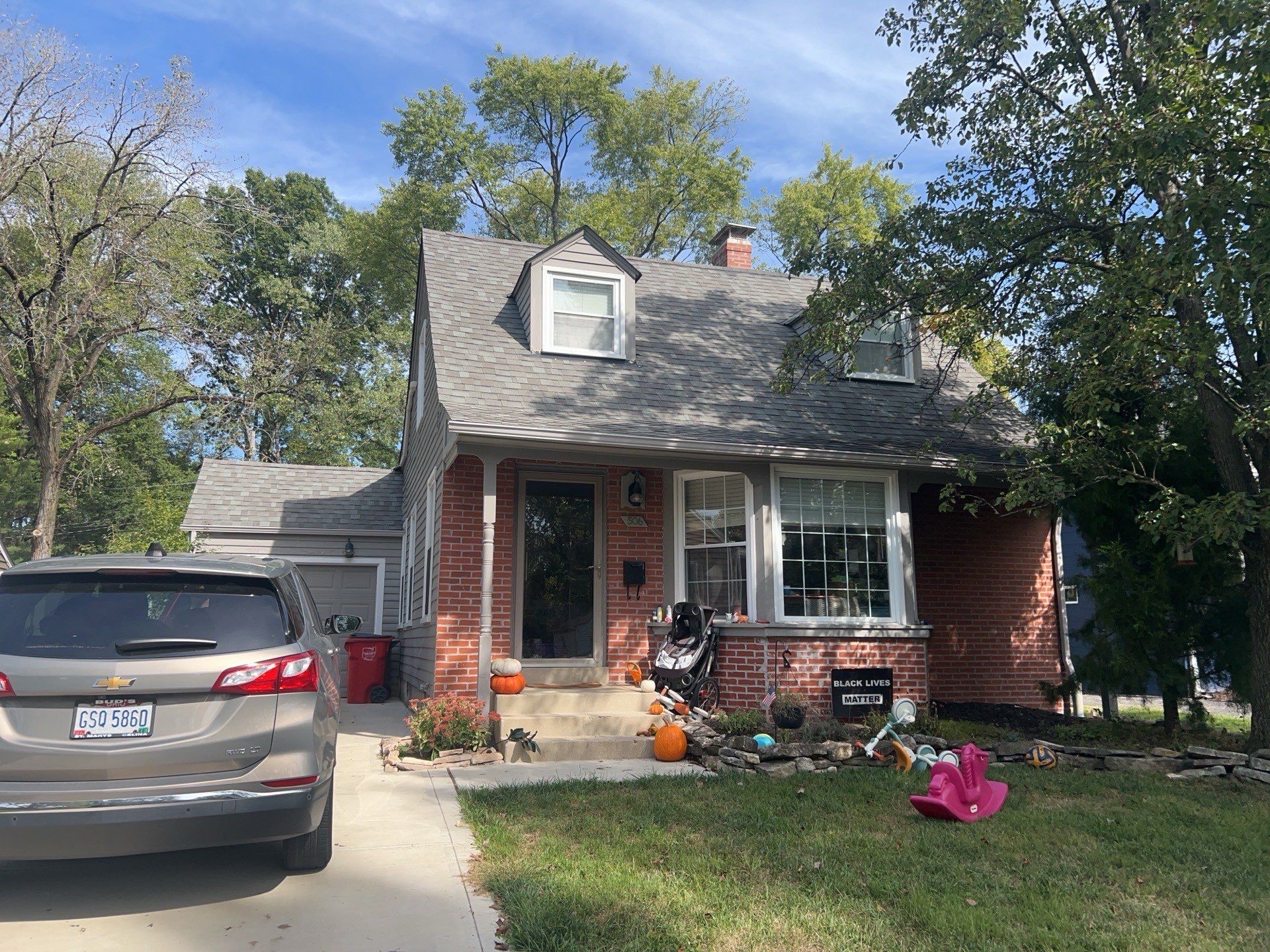 Front of the brick-front home with dormers before roof and siding restoration