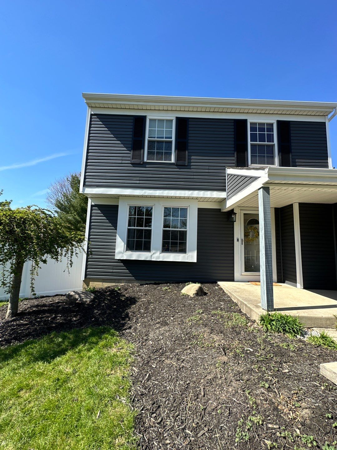Front entry of a two-story Gahanna home after roofing and siding renovation, with dark blue-charcoal siding and white trim