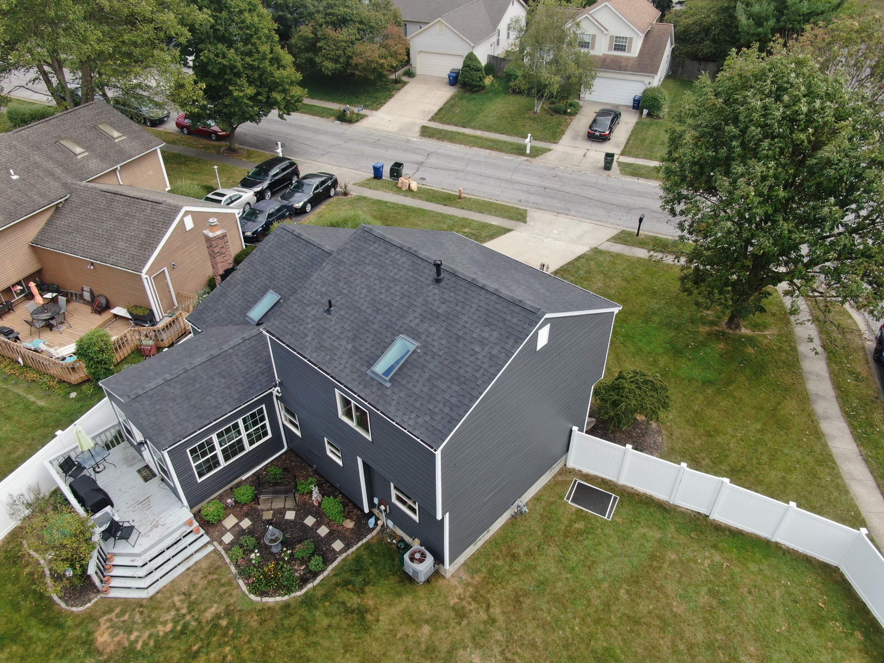 Aerial rear view of the finished home showing the new roof and dark siding from above