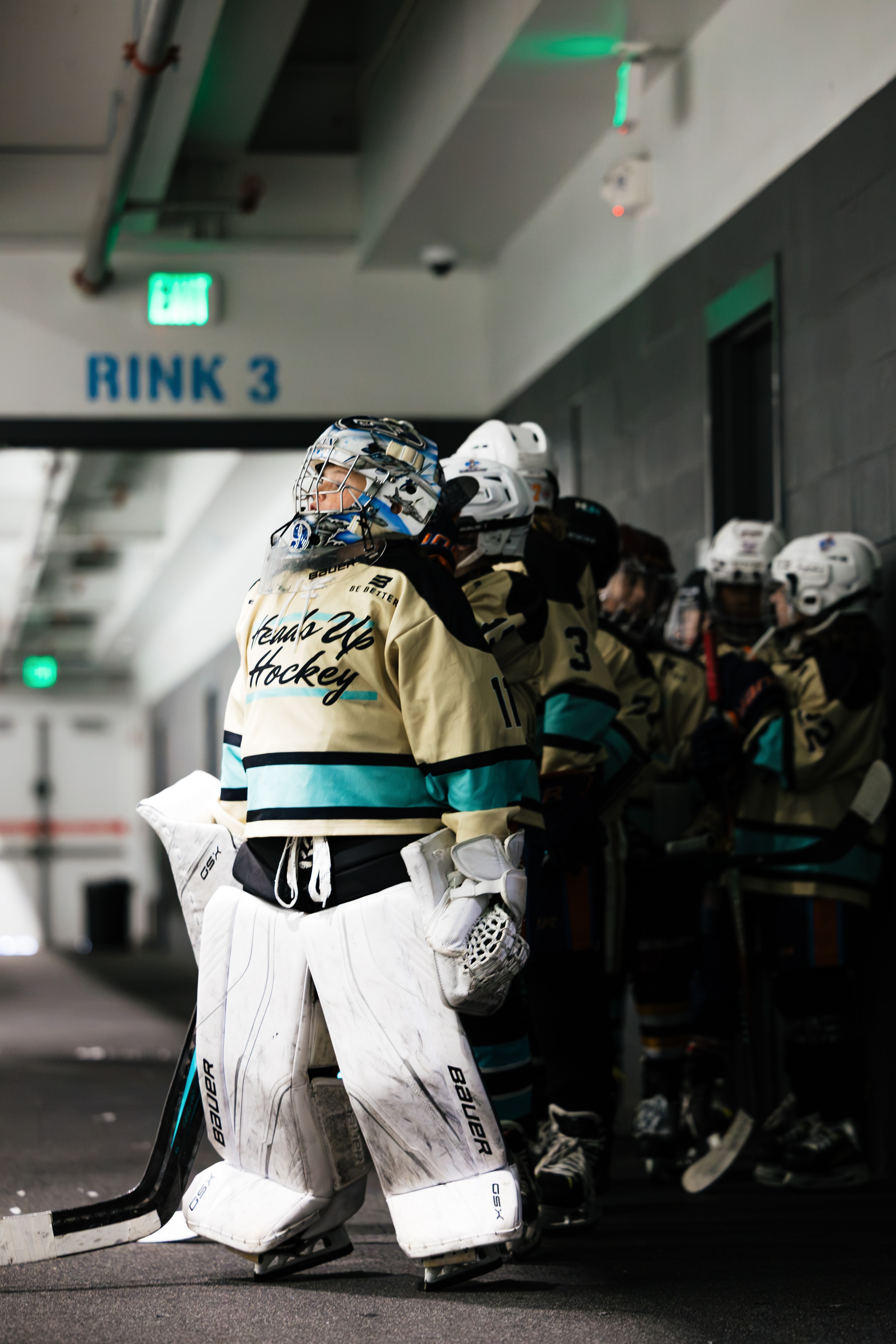Young hockey goalie and teammates heading toward the ice