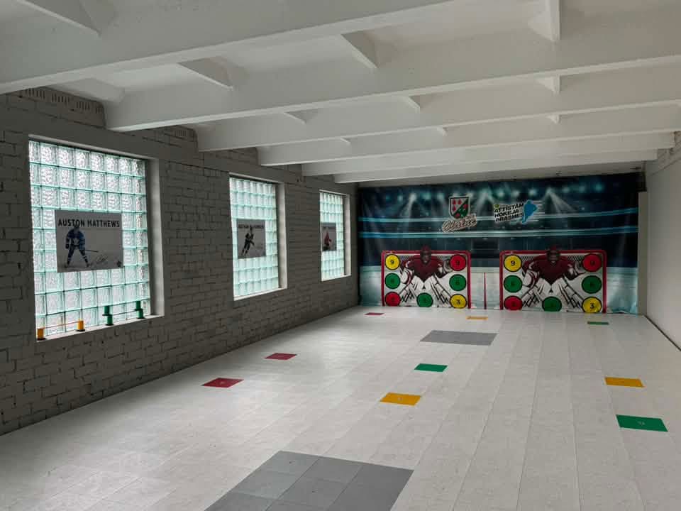 A dedicated home hockey practice area with a net and shooting surface
