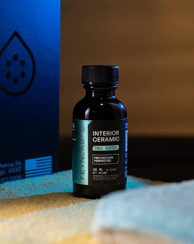 Interior ceramic coating bottle on a cloth beside its blue package