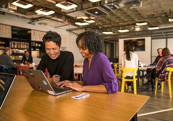 Two people collaborating at a laptop in a shared workspace, from Sopact's Audible customer story.