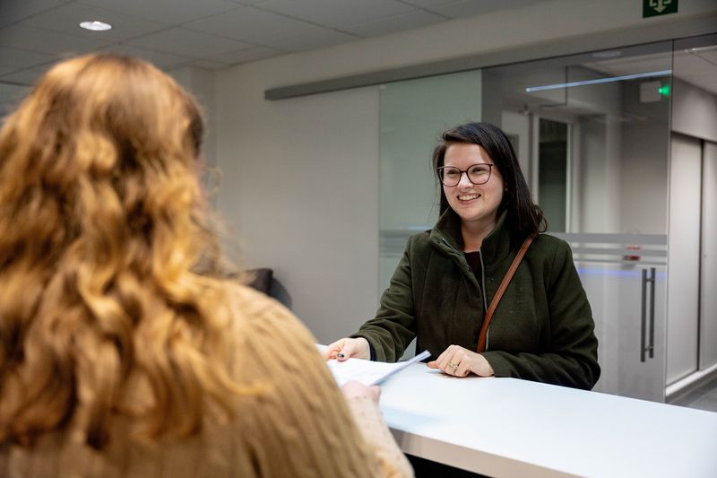 Collega verwelkomt een bezoeker aan het onthaal