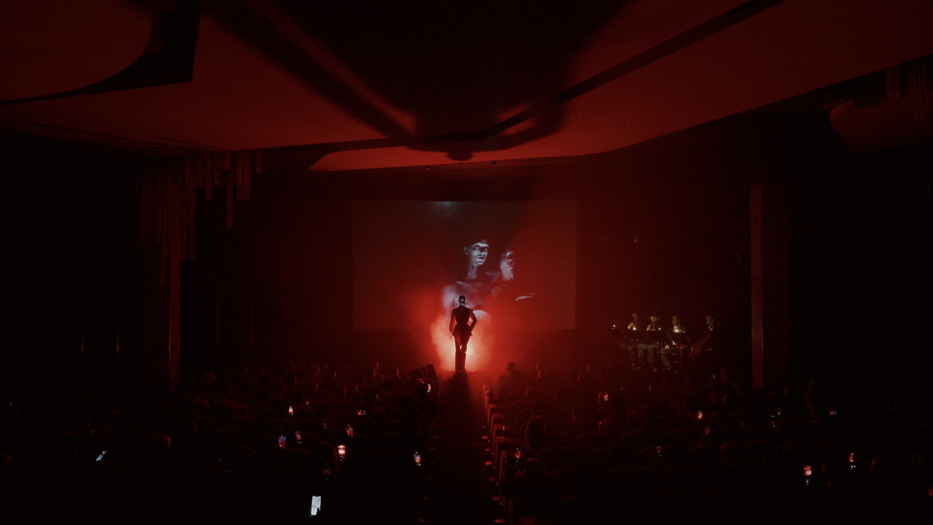 A performer silhouetted beneath the Nighthawk projection inside Cinema Le Balzac.