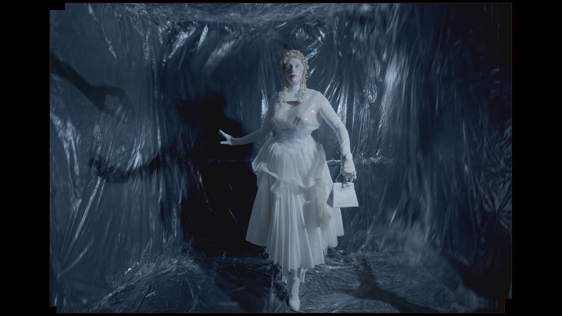 Nighthawk: a full silhouette in a white dress against a reflective blue backdrop.