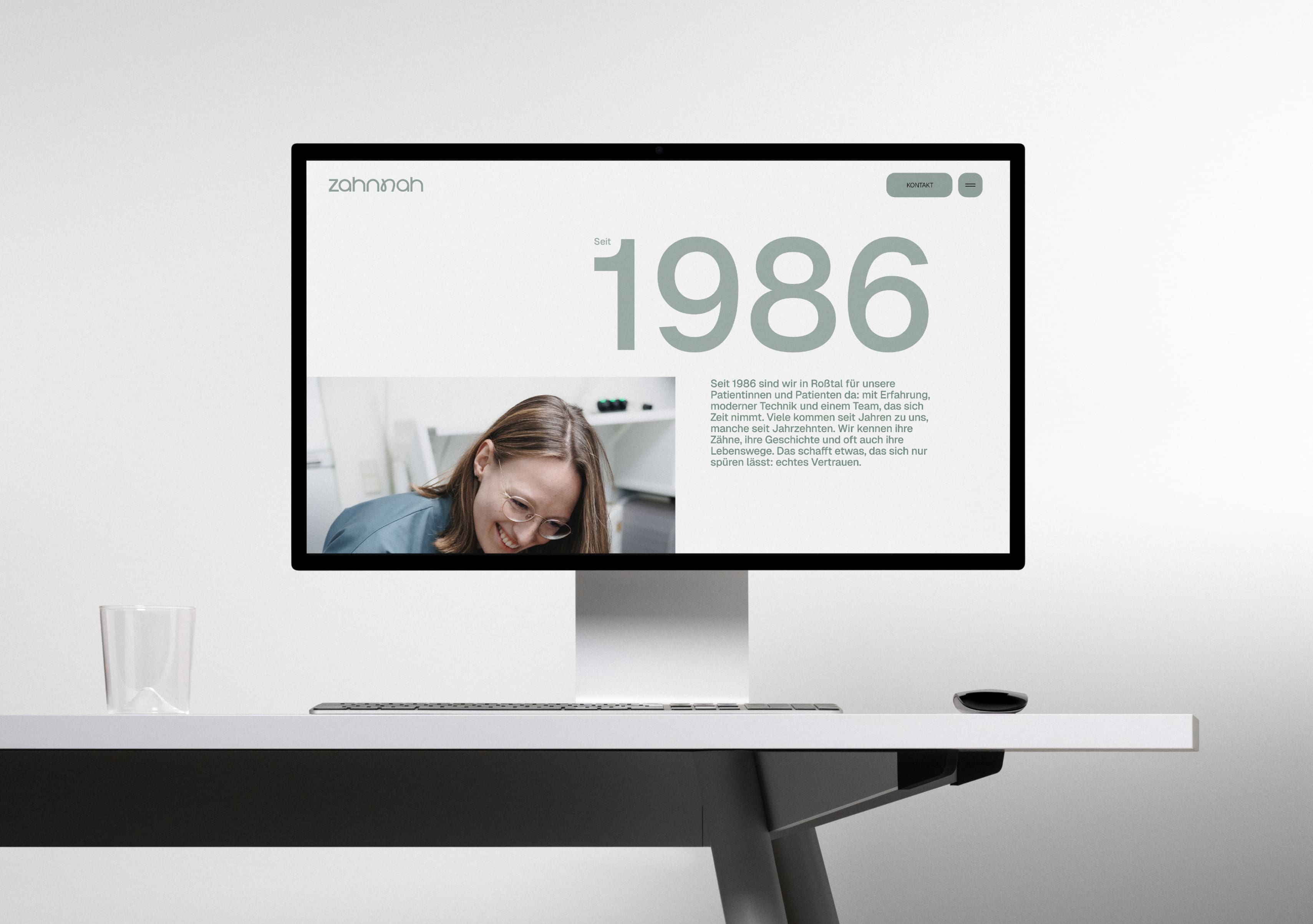 Website der Zahnarztpraxis Zahnnah auf einem Monitor an einem hellen Schreibtisch.