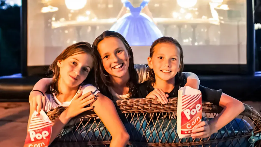 Families watching a holiday movie on a giant outdoor screen at night