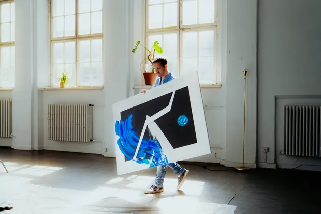 Pippo Kudi trägt ein fertiges Gemälde durch sein Atelier