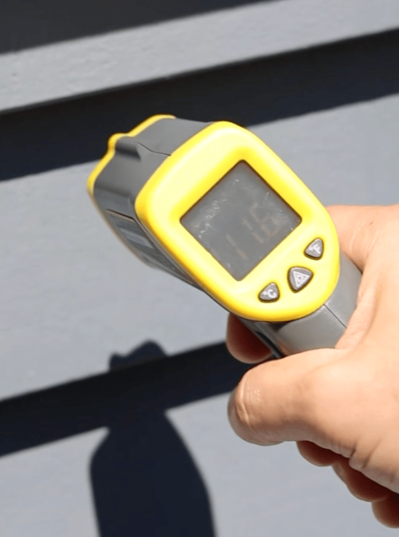 Infrared thermometer checking exterior surface temperature before painting