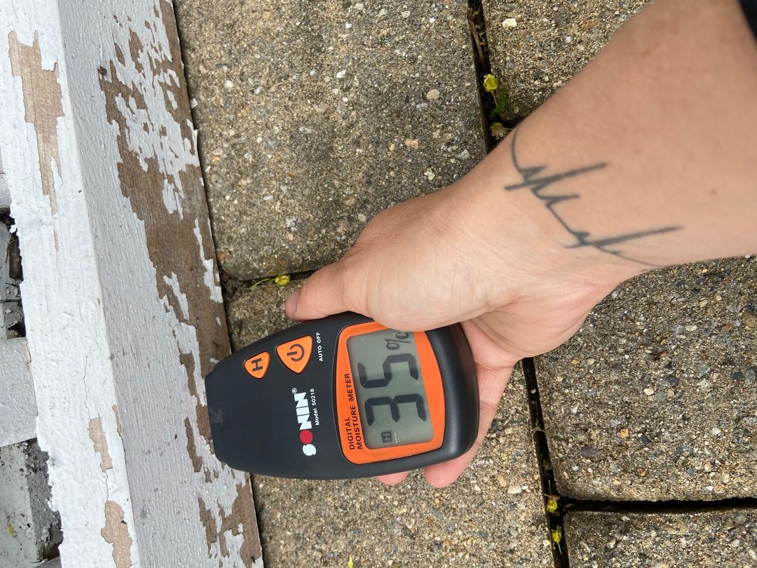 Moisture meter reading on exterior siding before painting
