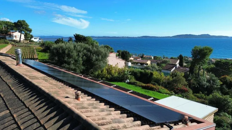 Panneaux photovoltaïques sur une toiture en tuiles avec vue sur le littoral à Carqueiranne.