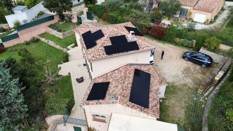 Vue aérienne de panneaux photovoltaïques répartis sur plusieurs pans de toiture.