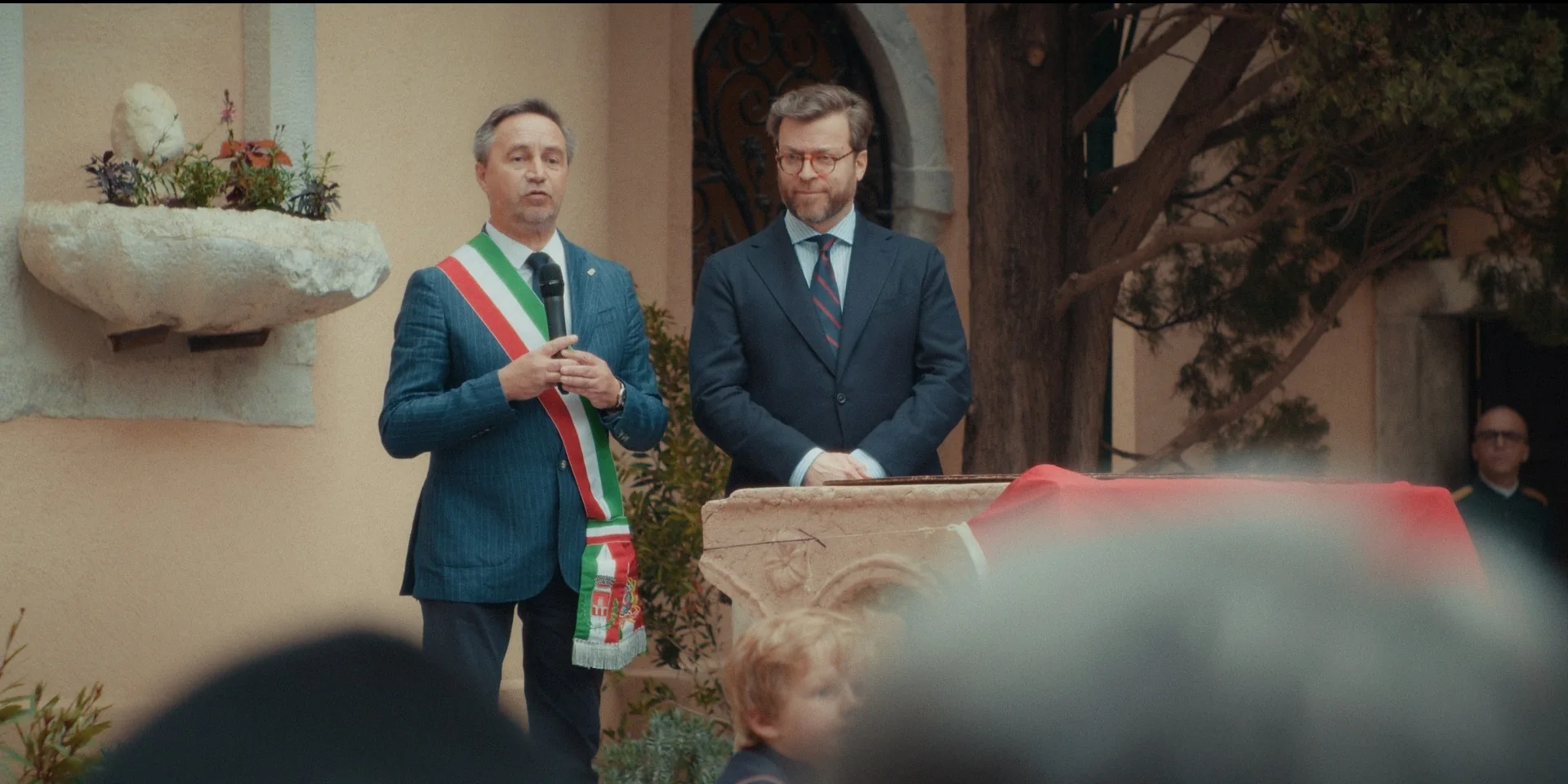 Rappresentante istituzionale con fascia tricolore parla al pubblico