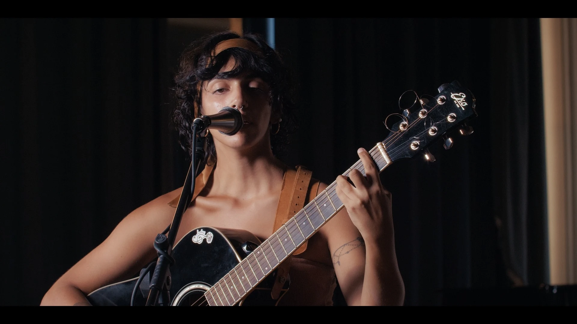 Anjelique canta Diamante al microfono accompagnandosi con la chitarra al Conservatorio Tartini