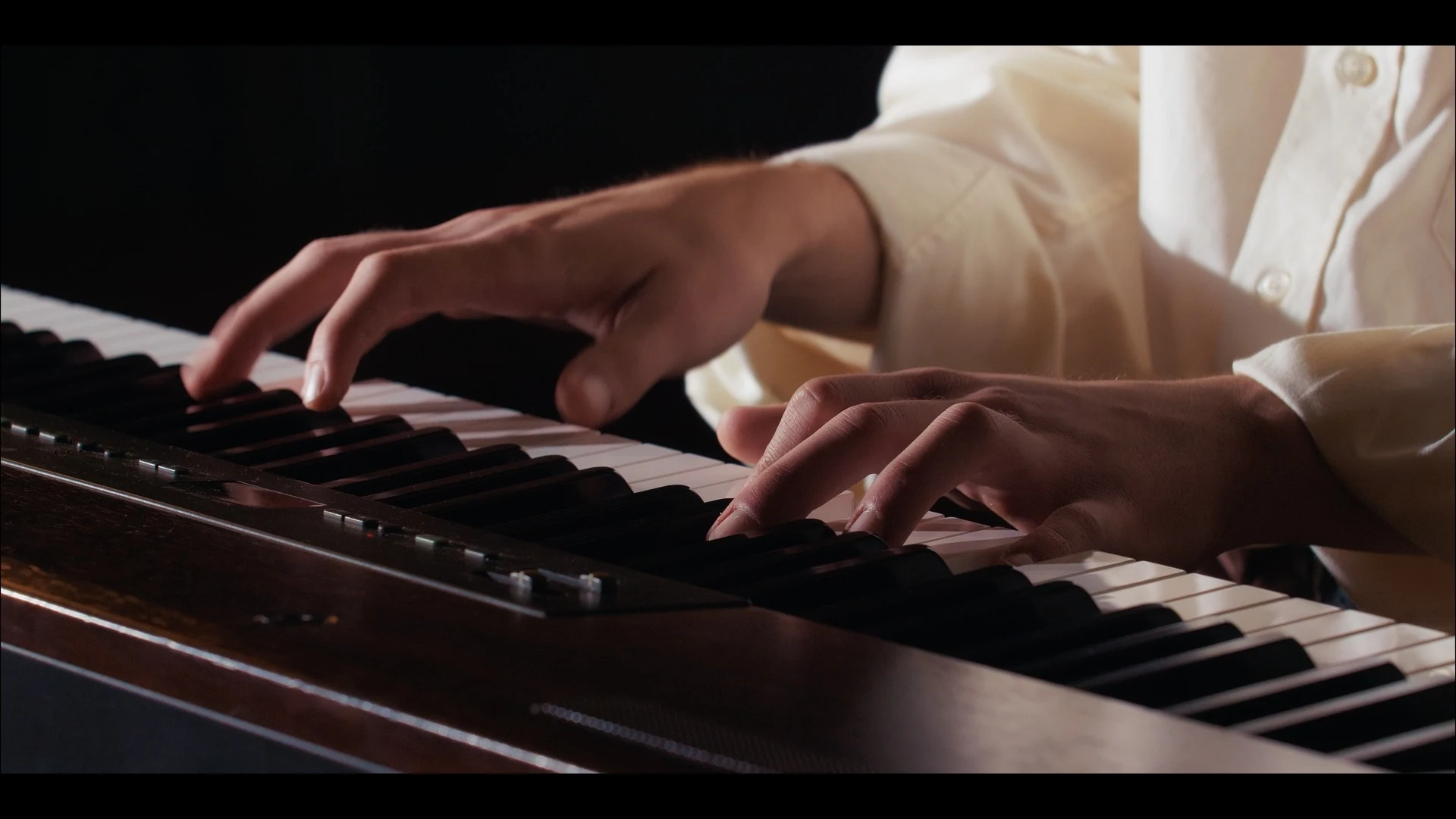 Primo piano delle mani sul pianoforte durante l'esecuzione musicale di Diamante