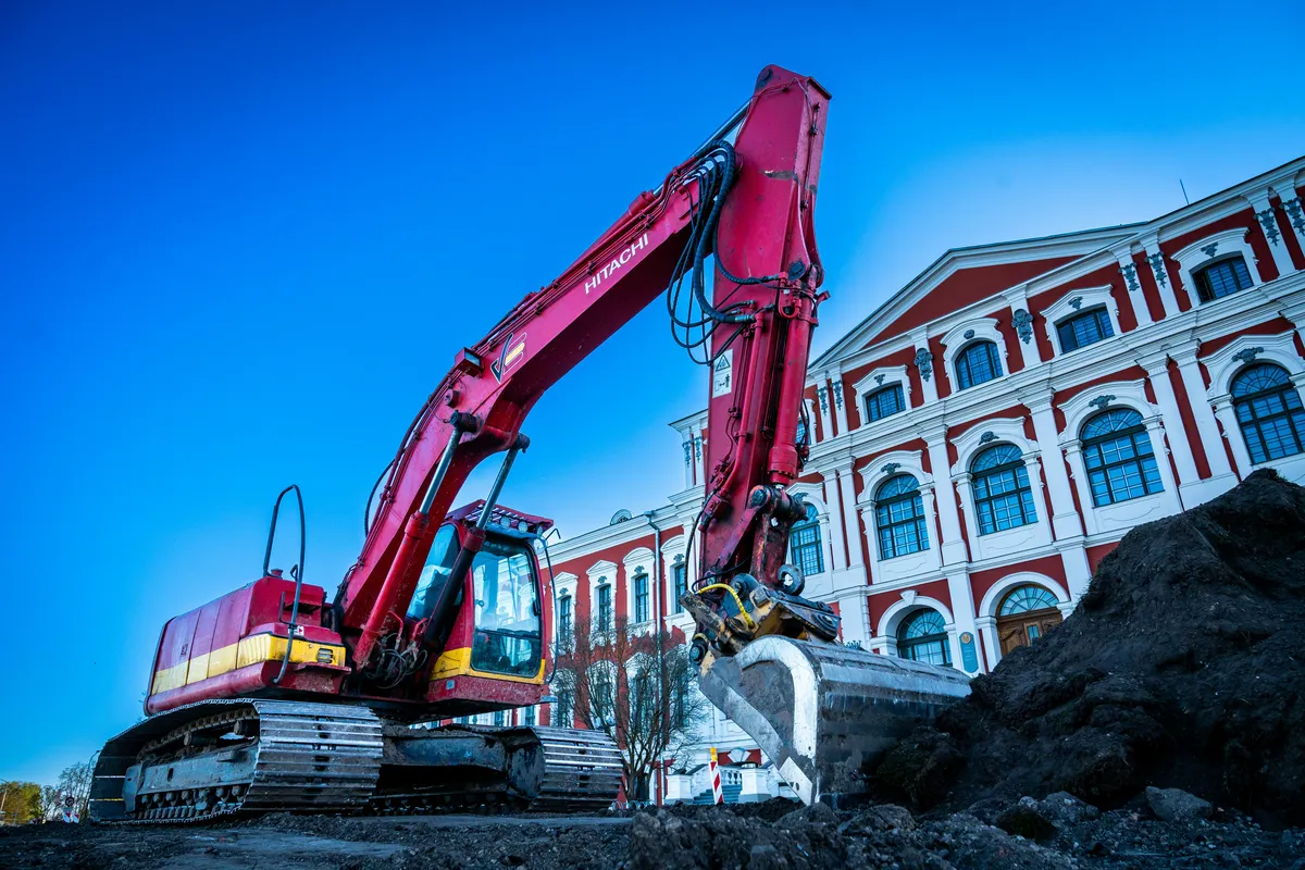 a red and yellow excavator sitting on top of a pile of dirt