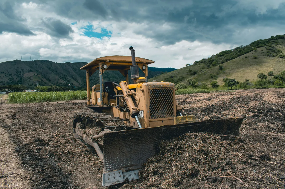 yellow and black heavy equipment on brown field under white clouds and blue sky during daytime