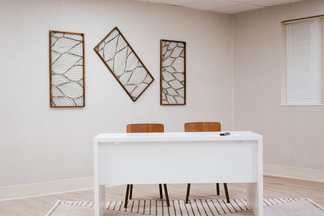 White desk, two wooden chairs and framed artwork at Dove Recovery