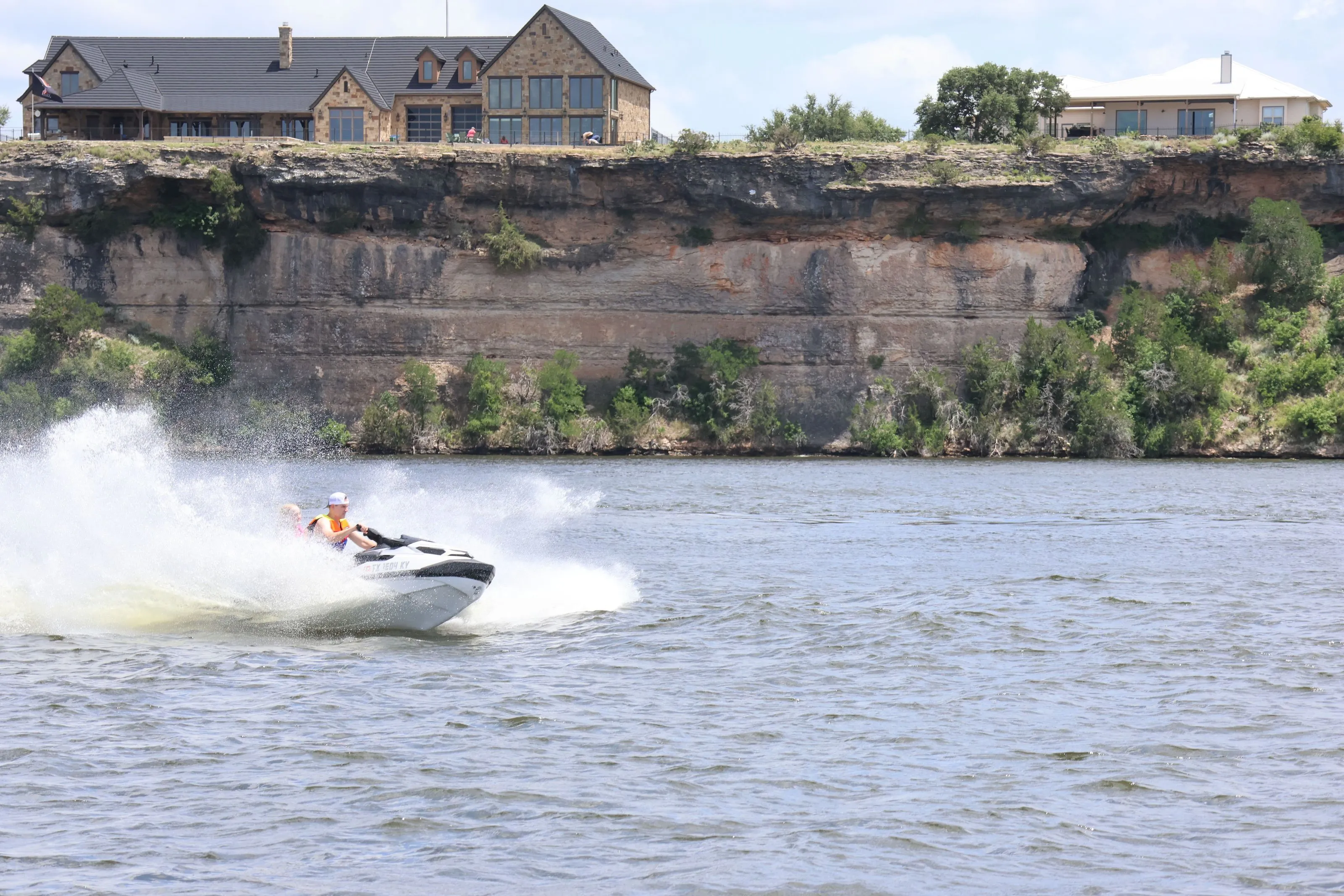 Jet ski on Possum Kingdom Lake below limestone cliffs and hilltop homes