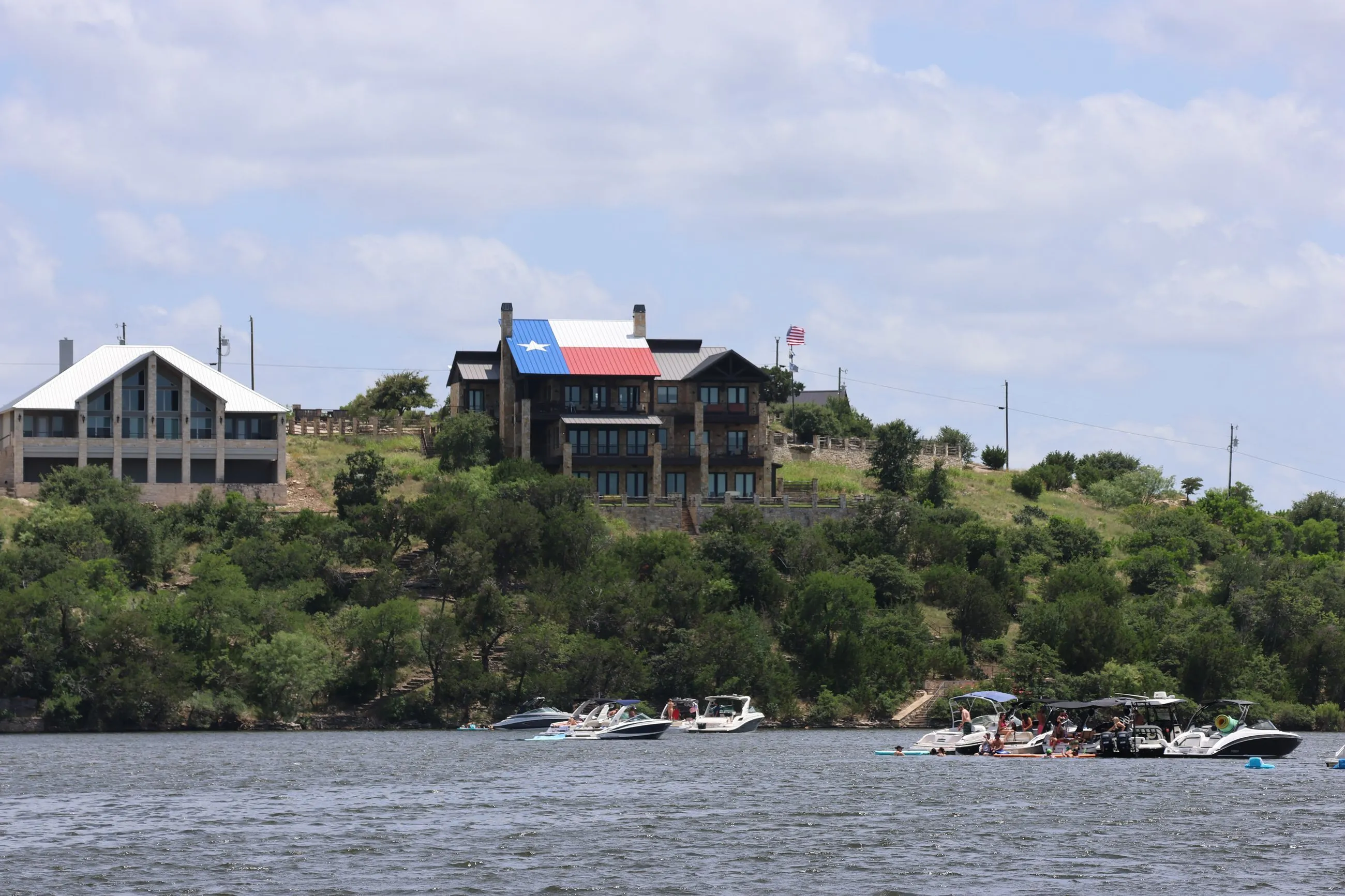 Lakefront homes above a raft-up of boats on Possum Kingdom Lake