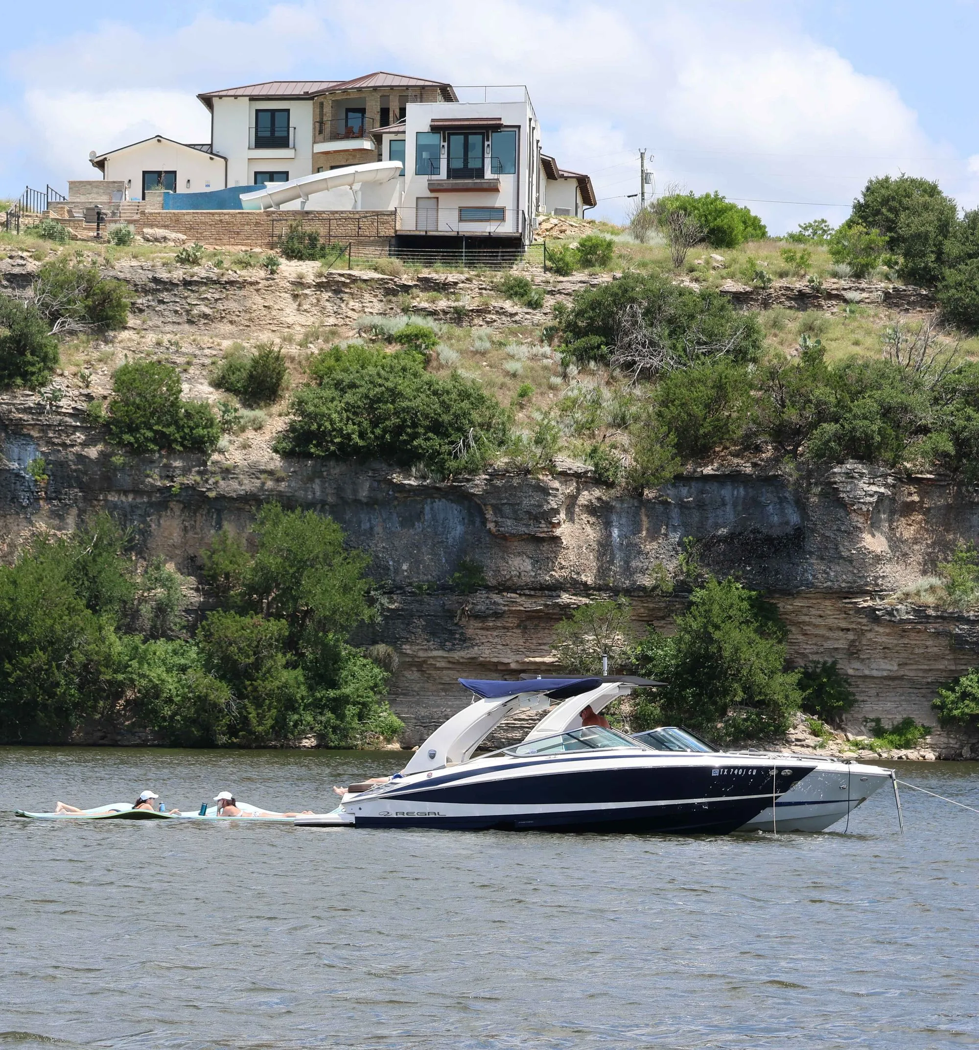 Boat anchored below a cliffside home on Possum Kingdom Lake