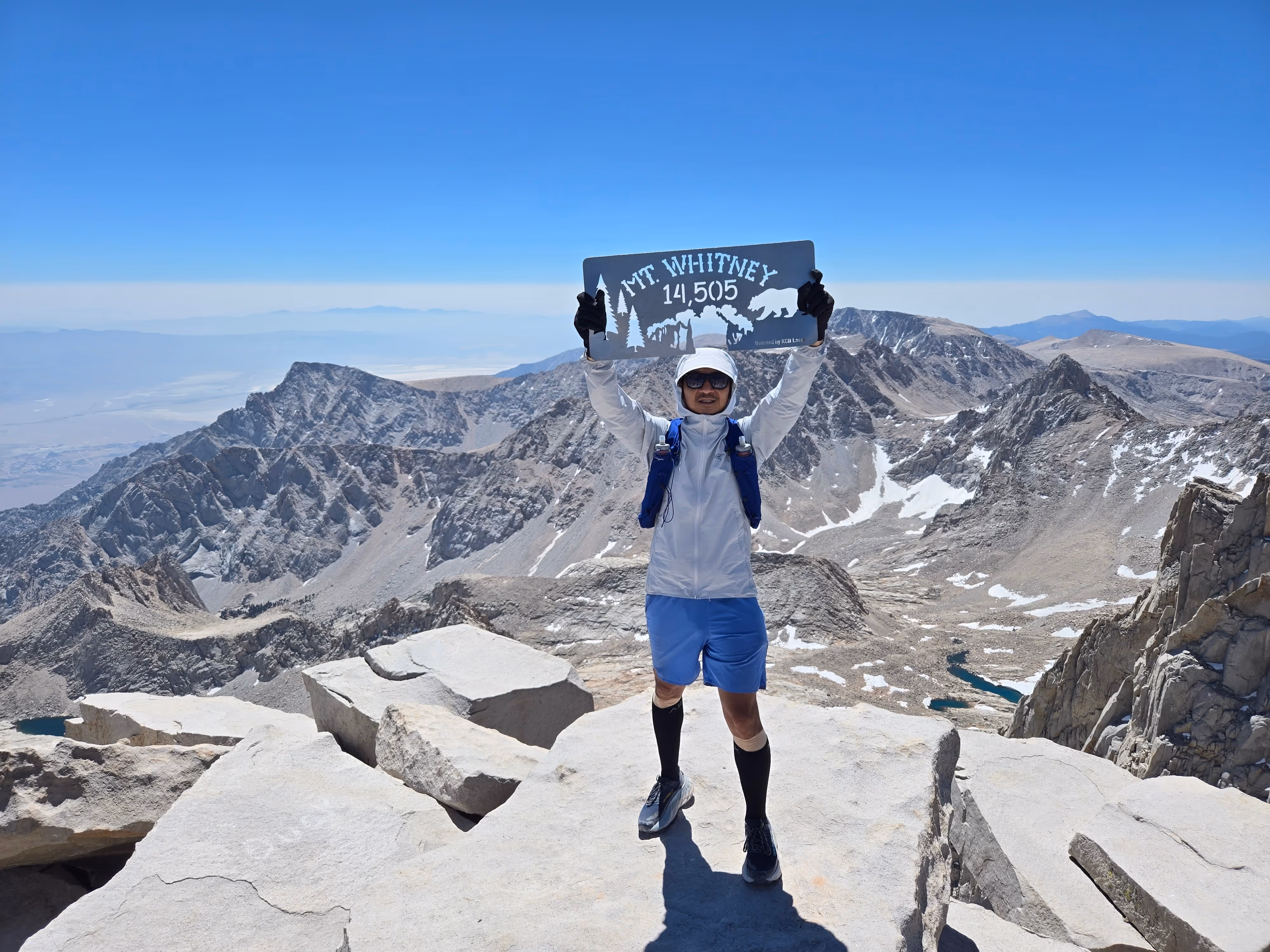 Mike Ye at the Mount Whitney summit sign with arms raised