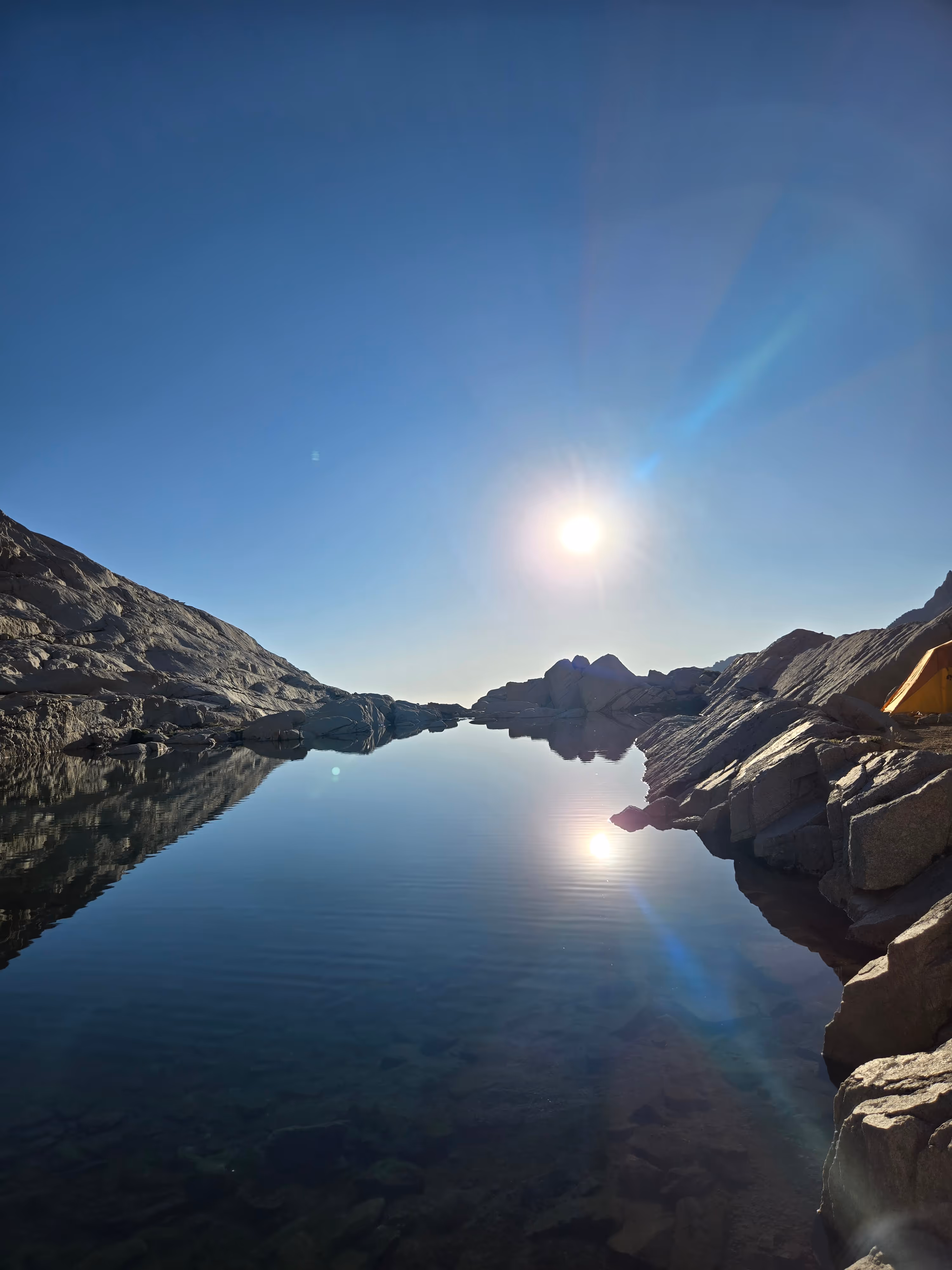 Morning sunlight reflected in an alpine lake beneath mountain ridges