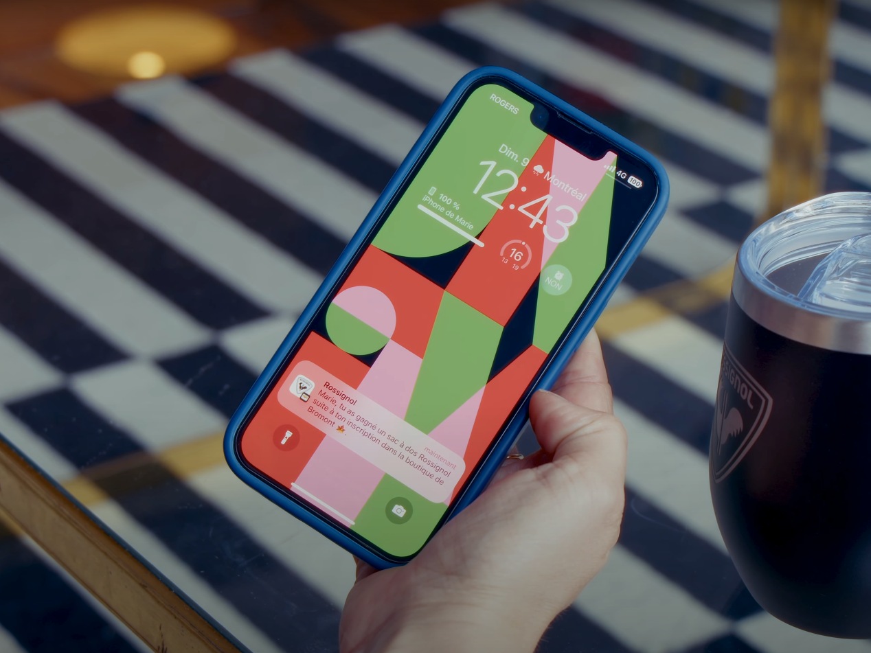 Main tenant un iPhone dont l écran verrouillé affiche une notification Wallet
