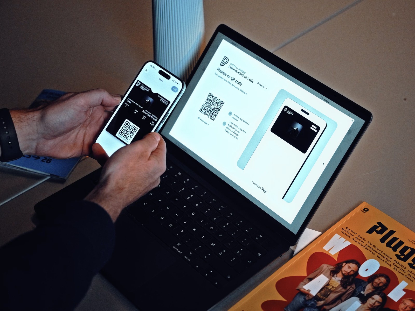 Une spectatrice présente son billet de concert Wallet sur iPhone, devant un écran affichant le QR code, à la Philharmonie de Paris