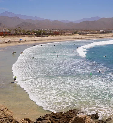 Playa del Pacífico cerca de Todos Santos con personas practicando surf