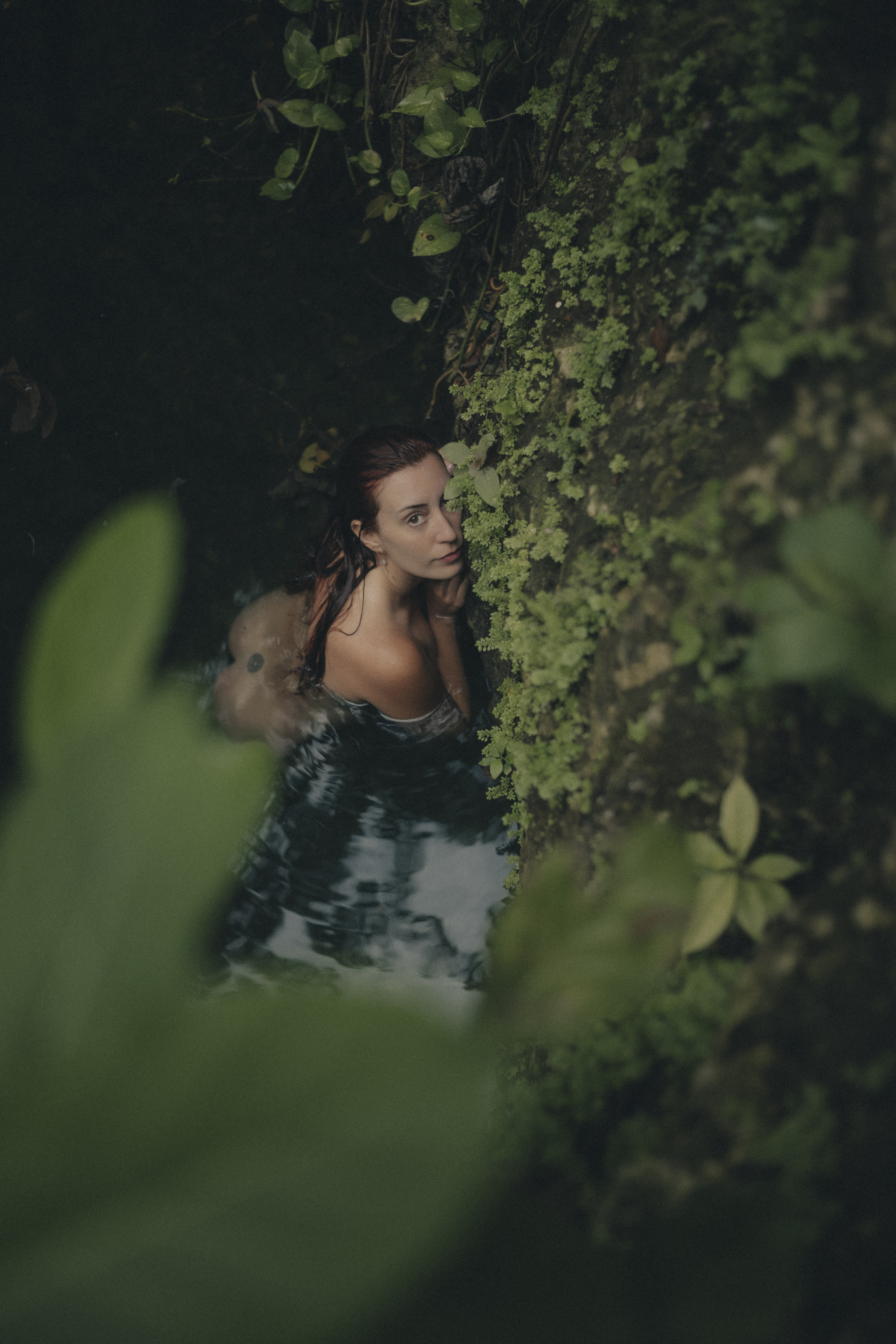 Delfina looking toward the camera beside moss-covered rock