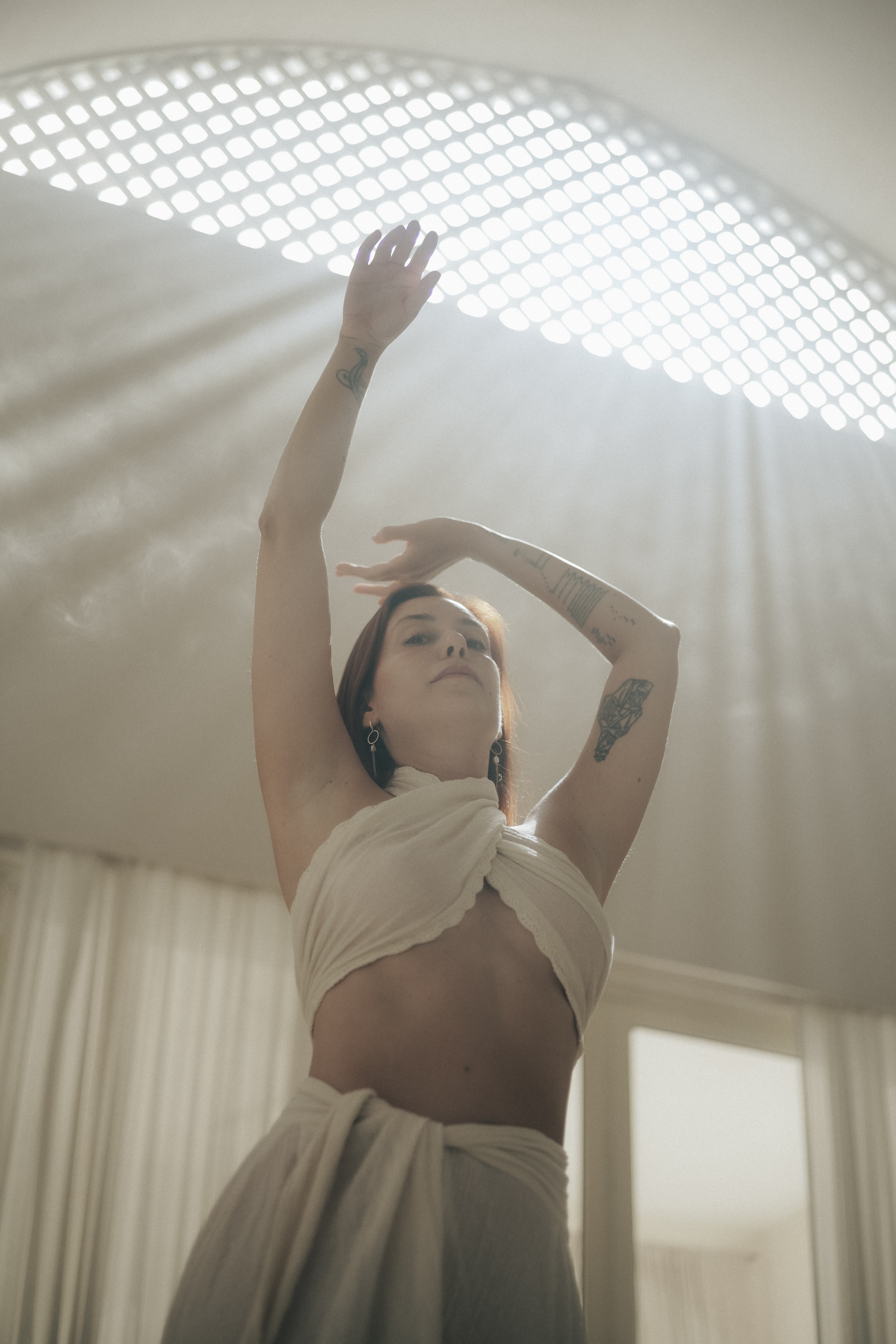 Delfina in light with arms raised