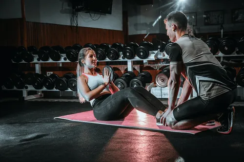Mujer entrenando con un entrenador personal en una sala de pesas