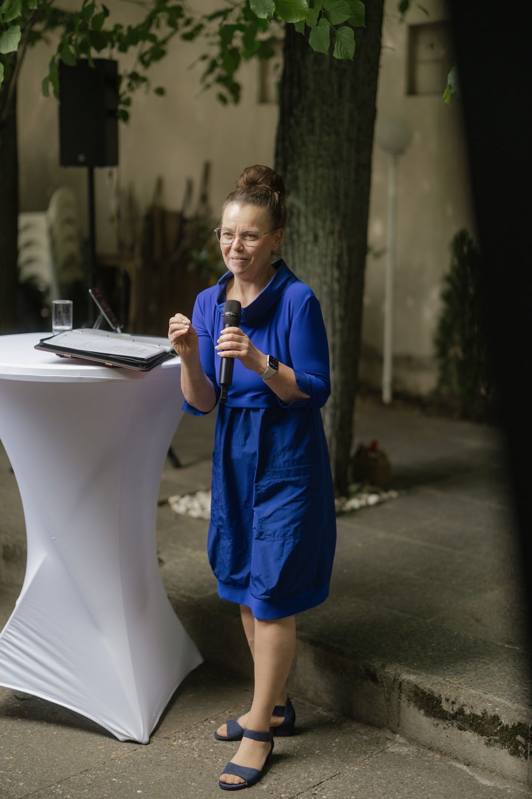 Kati Kreyser spricht mit Mikrofon und Redemappe am Stehtisch