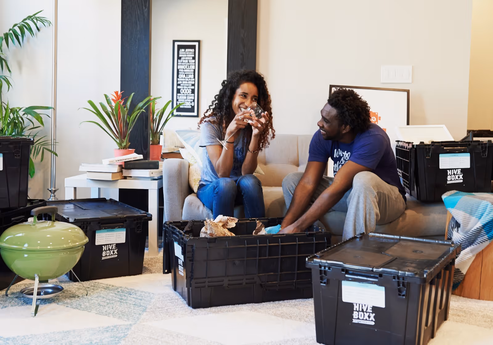 Two people sorting belongings into reusable moving bins.