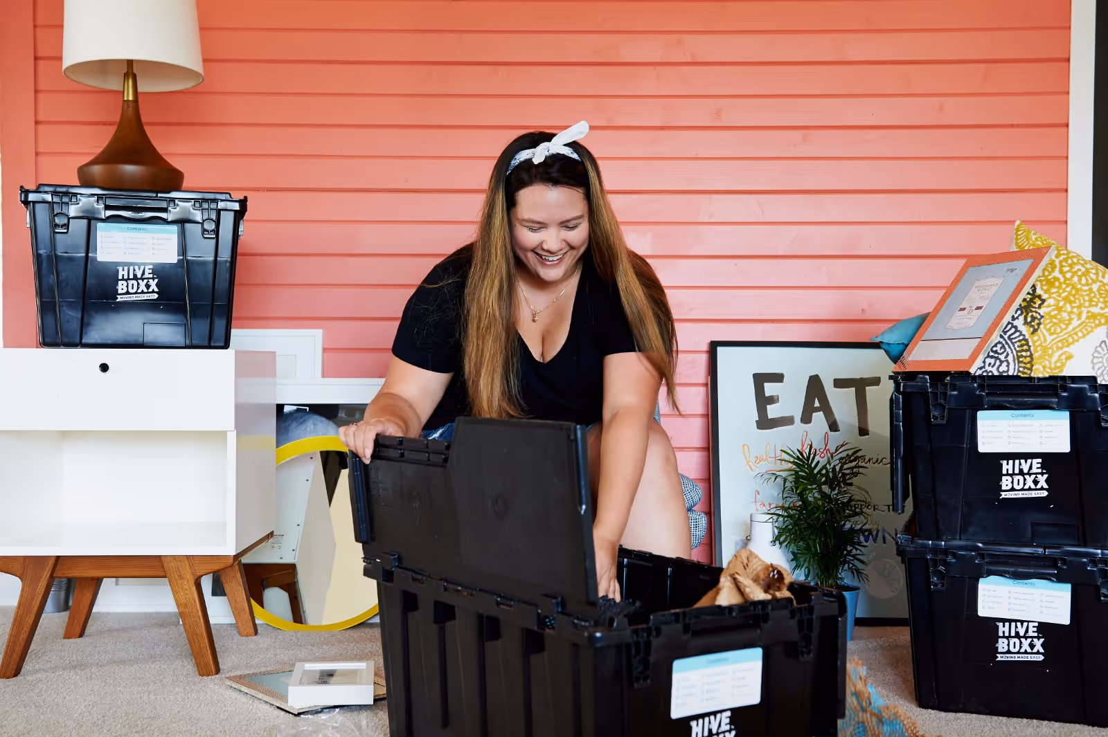 A woman unpacking a HiveBoxx bin in a bright living space.