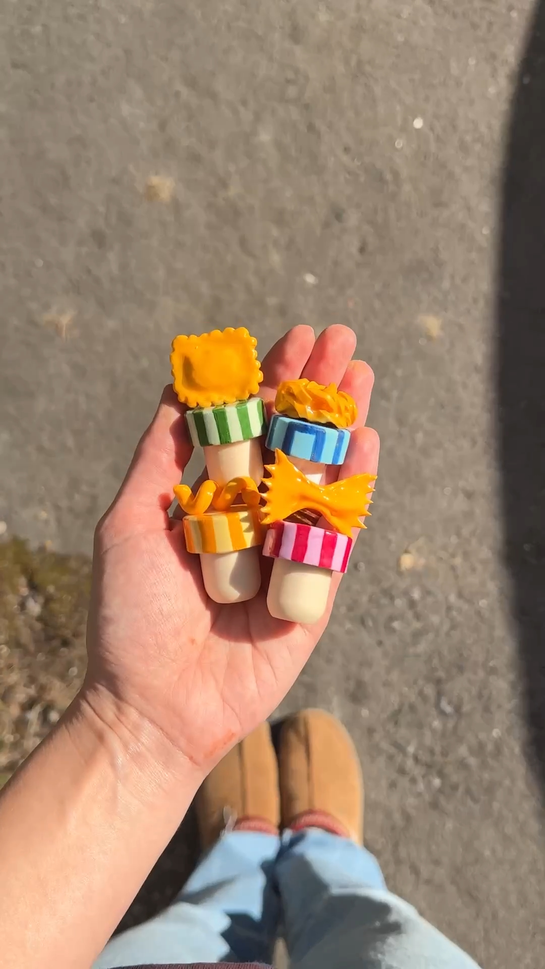 five handmade clay wine stoppers shaped like different pasta, held in one hand