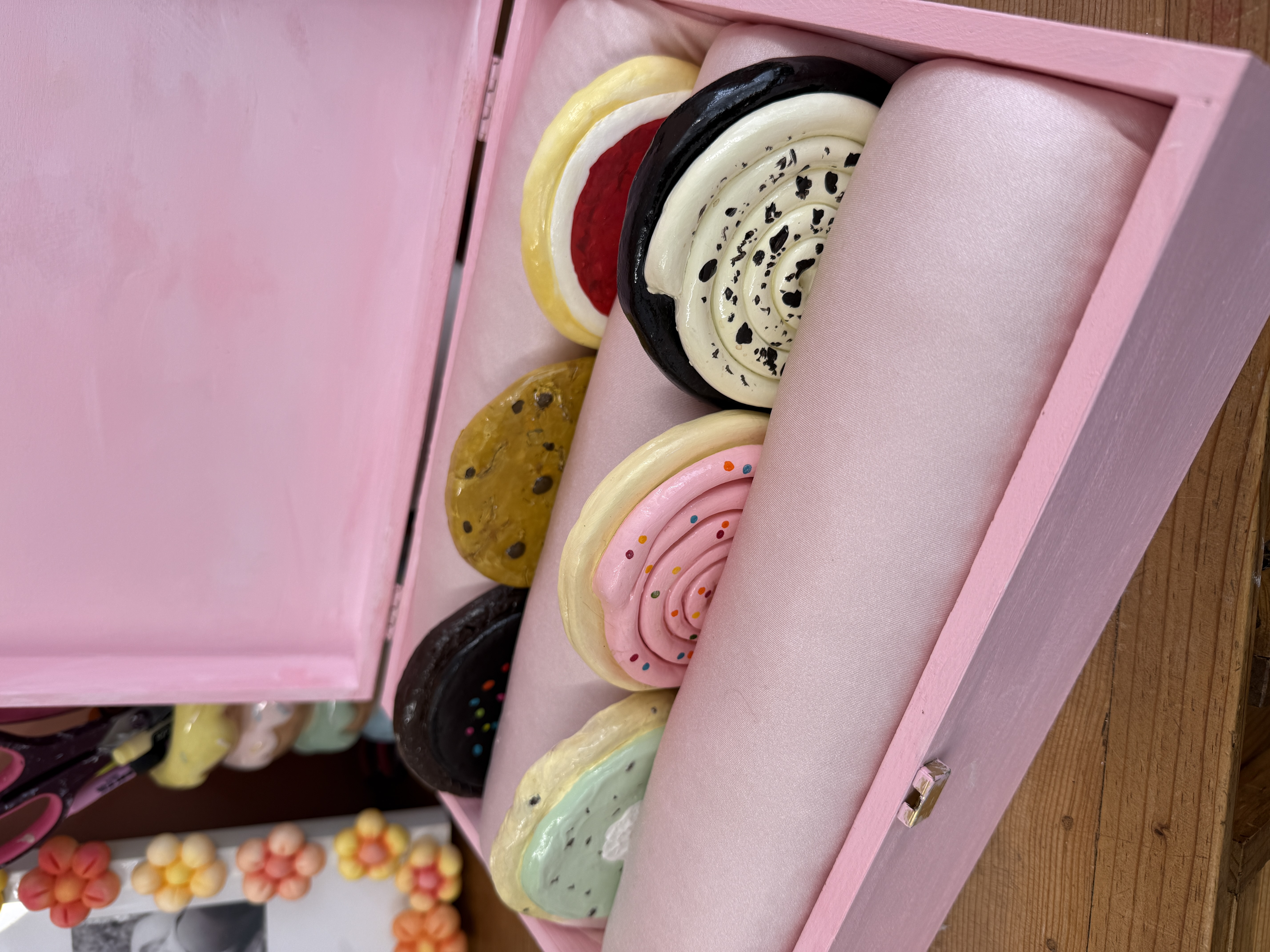 six handmade clay coasters painted to look like filled cookies, arranged in a pink lined gift box