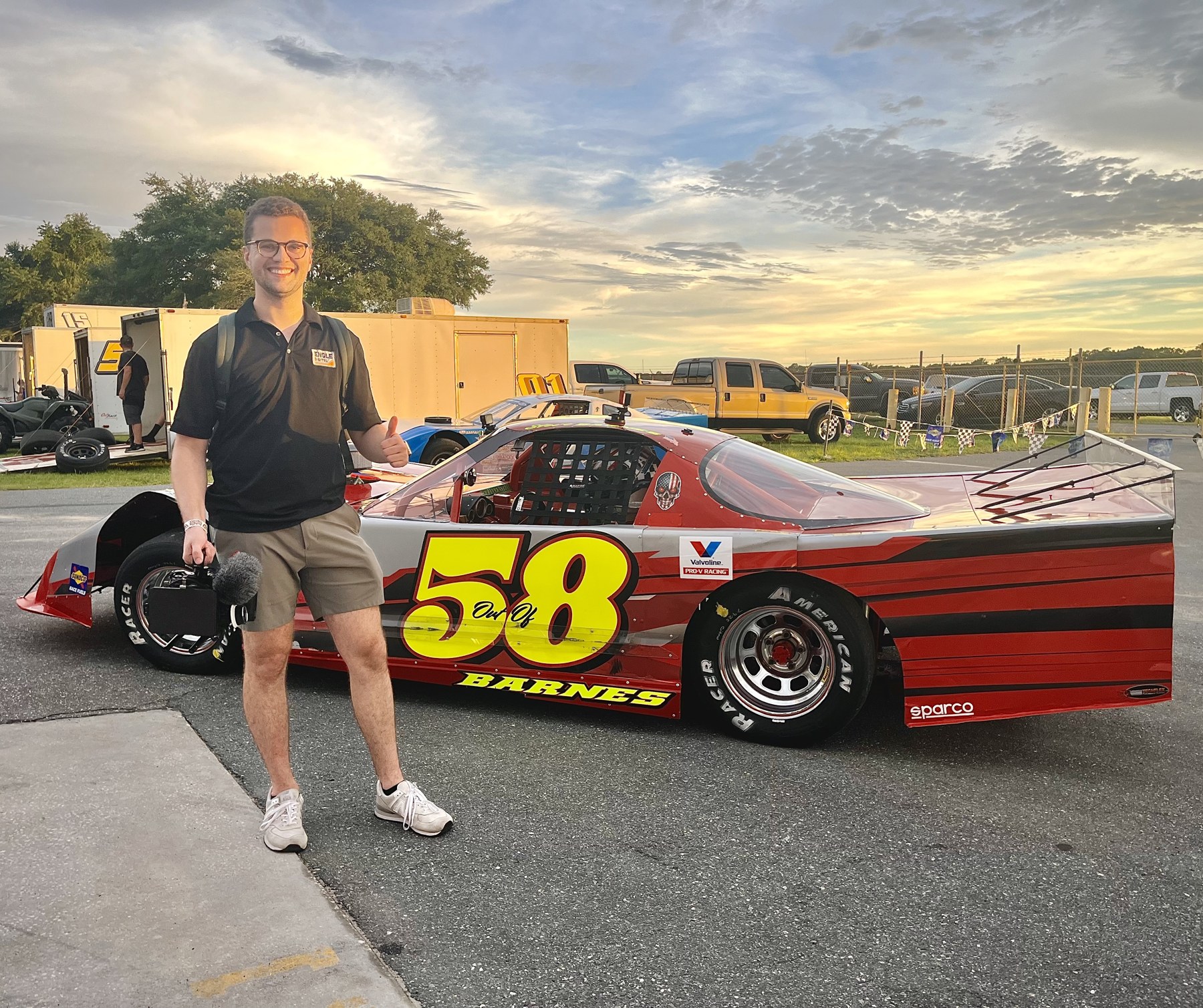 Camera operator beside the number 58 race car at sunset