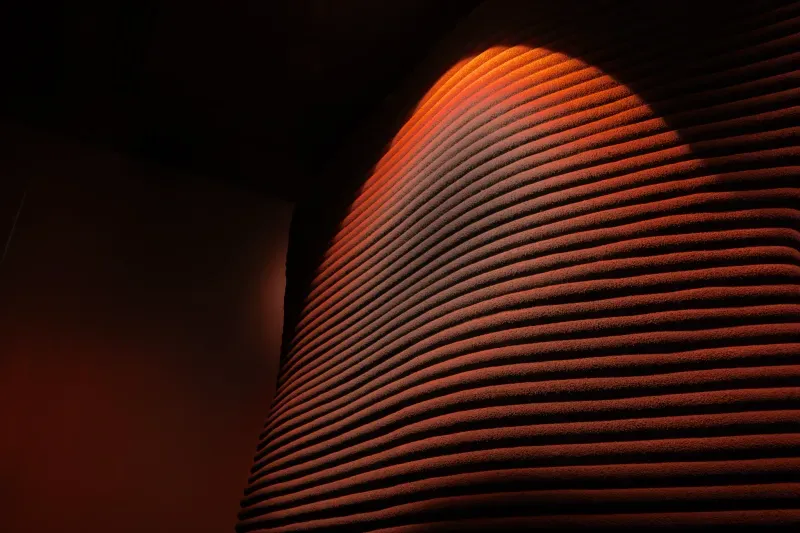 Curved canyon-inspired wall illuminated by warm red light