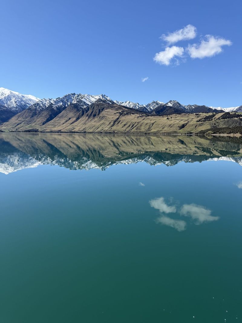 Mountains reflected in Lake Hāwea on a calm day